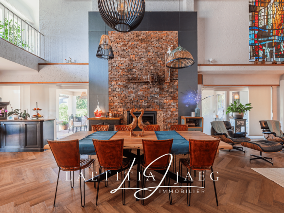 Intérieur d'une maison atypique avec une grande table en bois et un mur en briques.
