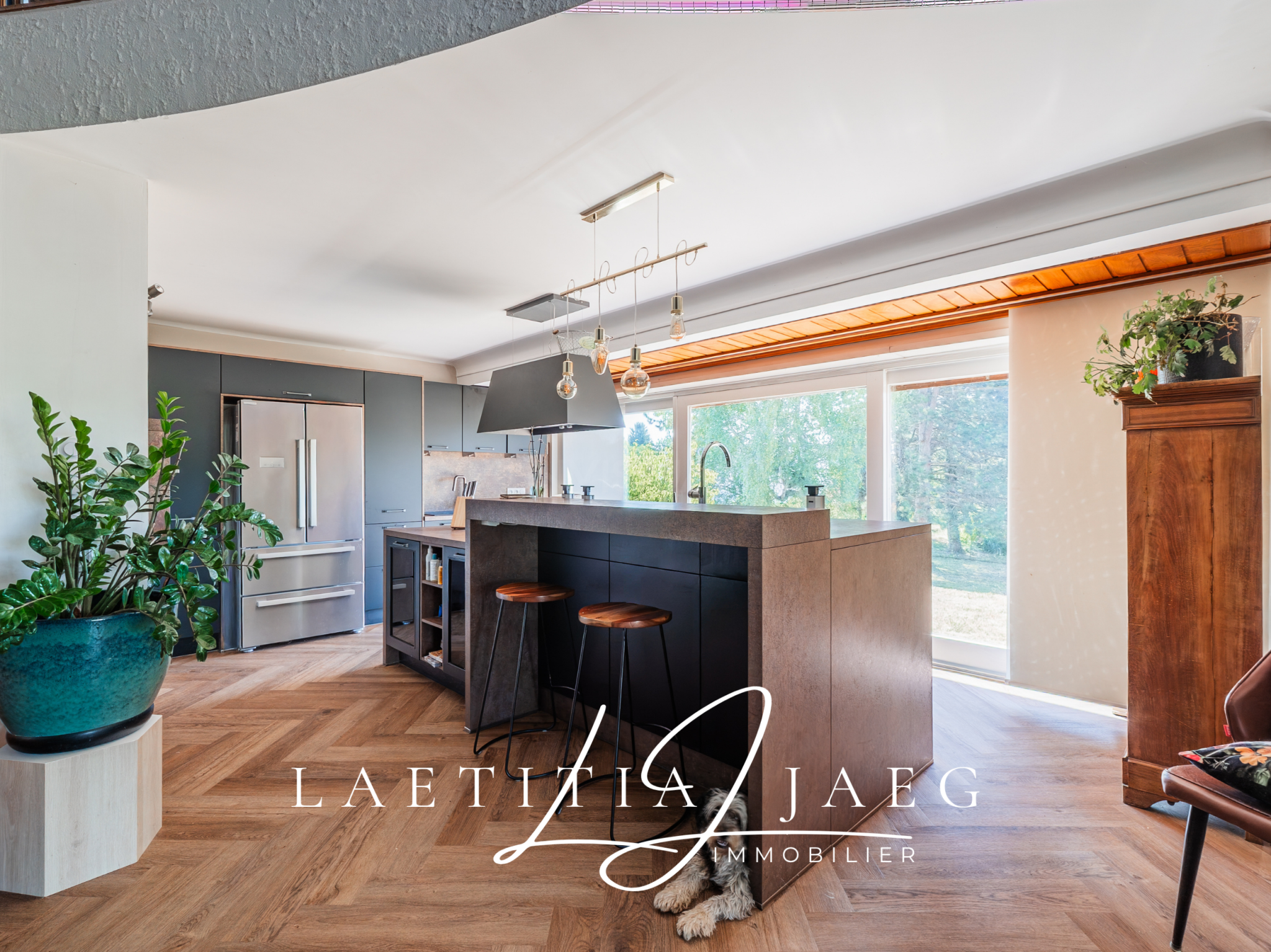 Cuisine moderne avec un bar et de grandes fenêtres donnant sur un espace naturel.