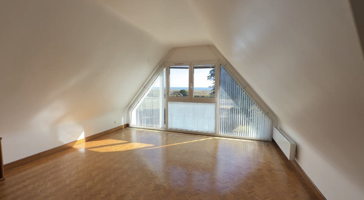 Chambre avec vue sur la mer à Sarzeau Intérieur d'une chambre avec vue sur la mer, grandes fenêtres et parquet en bois.
