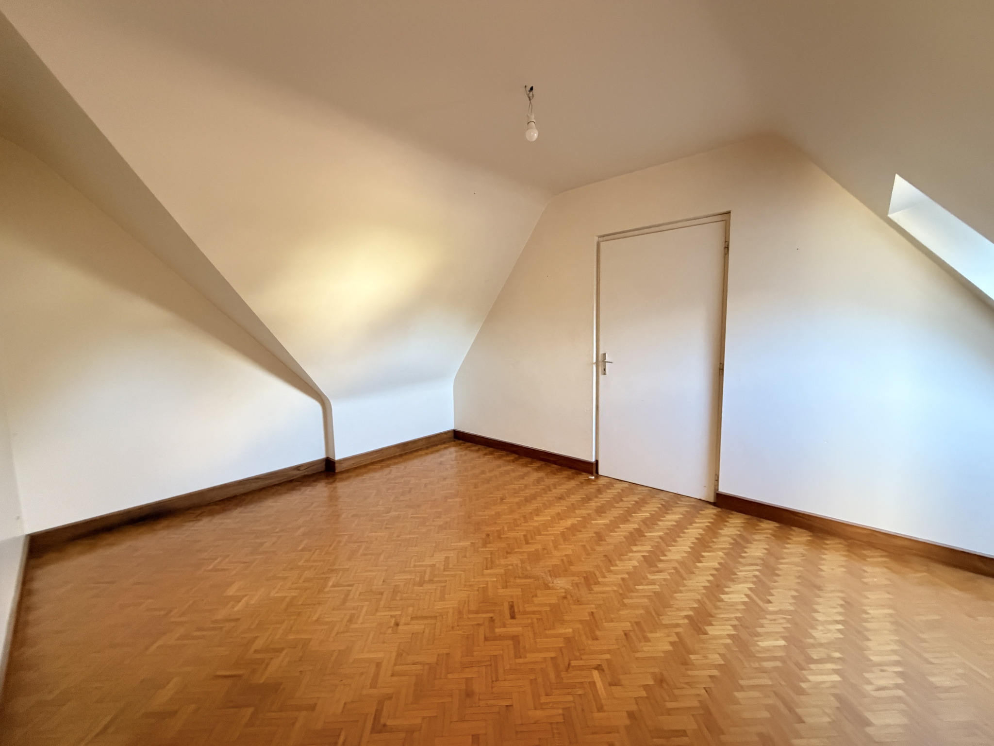 Chambre à Sarzeau Chambre spacieuse avec parquet en bois et murs blancs, sans meubles.