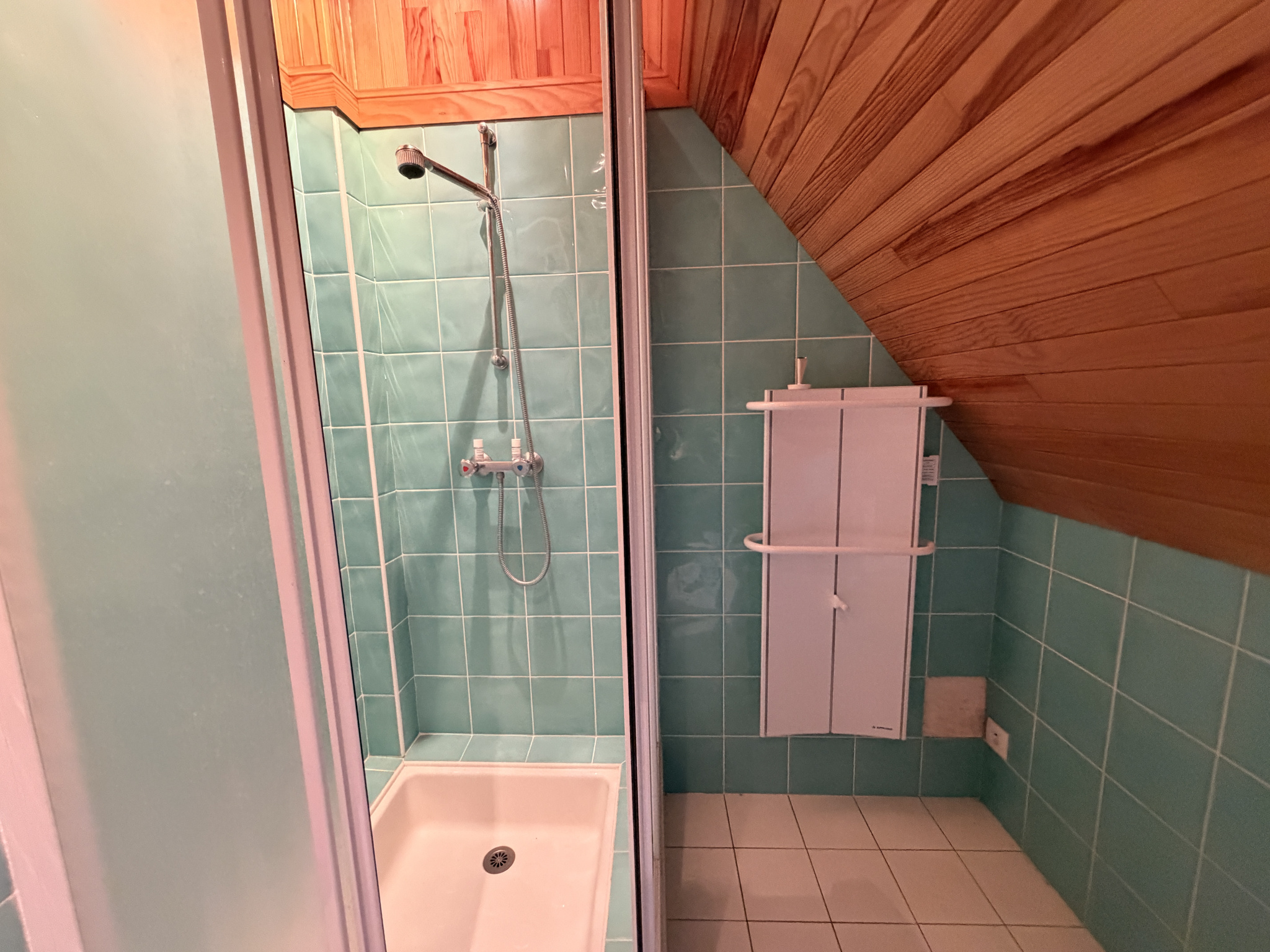 Salle de bain de la propriété à Sarzeau Salle de bain avec douche, carrelage vert et plafond en bois.