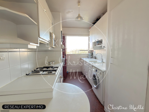 Kitchen of a rooftop apartment in Versailles, with white furniture and a view of the outside.