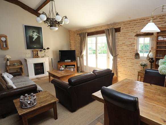 Interior of a house with living room and dining room, brick walls, wooden furniture.