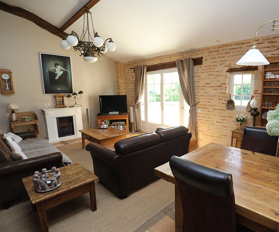 Interior of a charming house Interior of a house with living room and dining room, brick walls, wooden furniture.