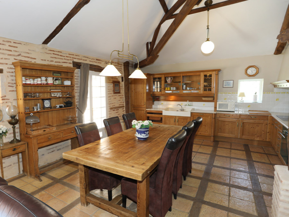 Interior of a spacious kitchen with wooden table and wooden storage, pendant lighting.
