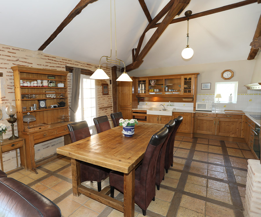 Kitchen of an estate on the banks of the Lot Interior of a spacious kitchen with wooden table and wooden storage, pendant lighting.
