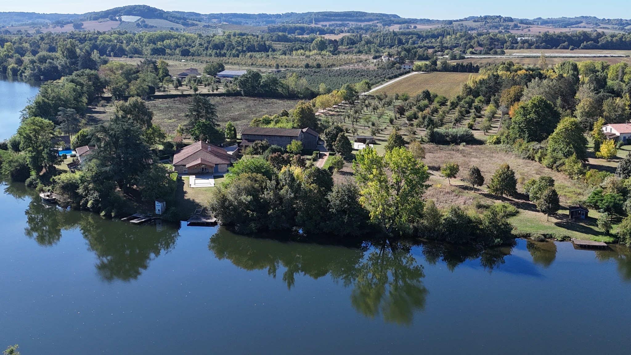 Exceptional estate on the banks of the Lot Aerial view of an estate of more than 7 hectares on the banks of the Lot with three houses and green spaces.