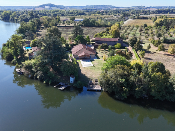 Aerial view of an estate of more than 7 hectares on the banks of the Lot river with houses and gardens.