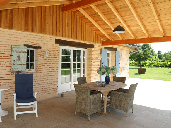 Wooden terrace with table and chairs, garden view in an estate on the banks of the Lot river.
