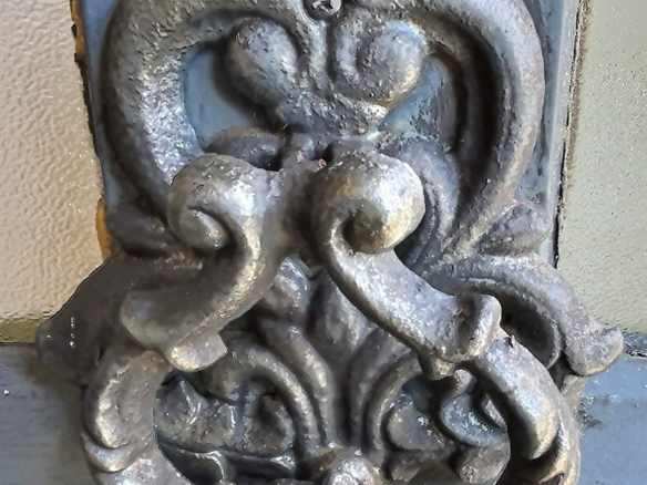 Poignée de porte en métal ornée, style historique, sur un fond de bois.