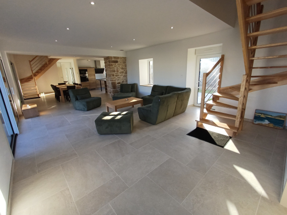 Intérieur d'une maison bretonne en pierre à Plougasnou, avec un grand séjour et un escalier en bois.