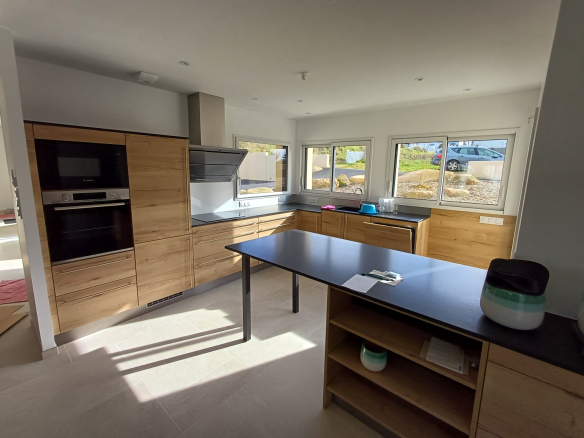 Cuisine moderne avec des meubles en bois et un plan de travail noir, lumineuse et spacieuse.