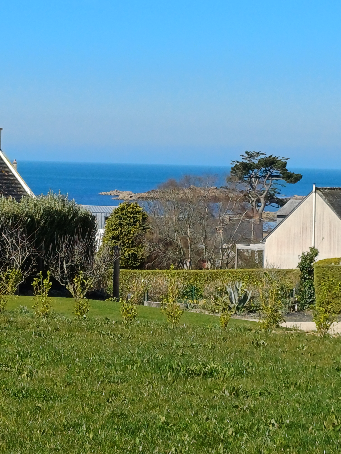 Vue mer depuis Plougasnou Vue sur la mer depuis une maison bretonne en pierre à Plougasnou, avec un jardin en premier plan.