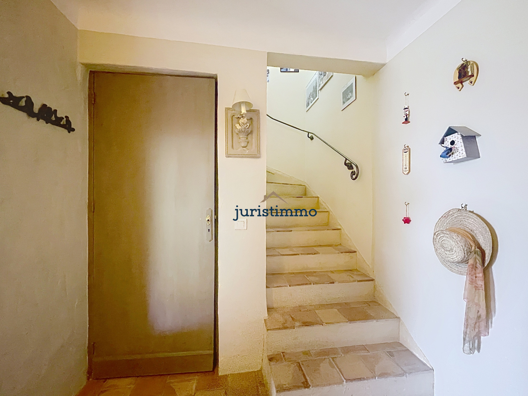 Intérieur d'une propriété avec un escalier et une porte en bois, décoré de chapeaux et d'objets muraux.