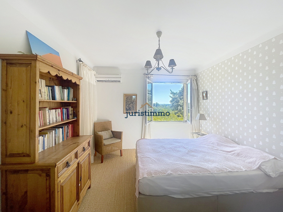 Chambre lumineuse avec vue sur la nature, bibliothèque en bois et lit double.
