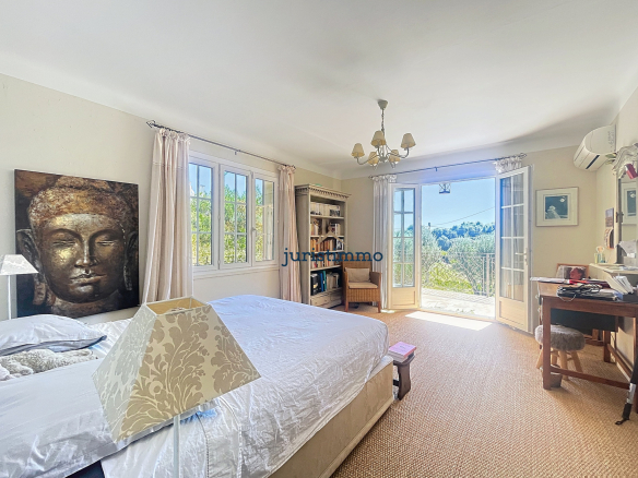 Chambre lumineuse avec vue sur la nature, décorée avec un tableau de Bouddha et un bureau.