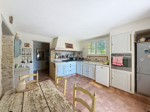 Cuisine spacieuse d'une propriété à Vacqueyras avec meubles en bois et appareils modernes.