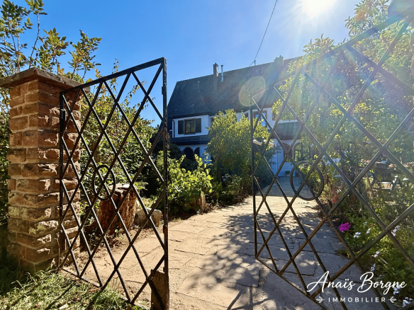Entrée d'un manoir néo-alsacien avec un portail en fer forgé et un parc arboré.
