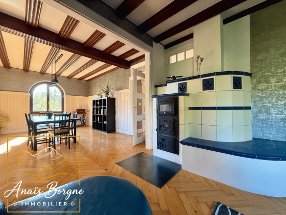 Intérieur d'un manoir néo-alsacien avec cheminée et salle à manger lumineuse.