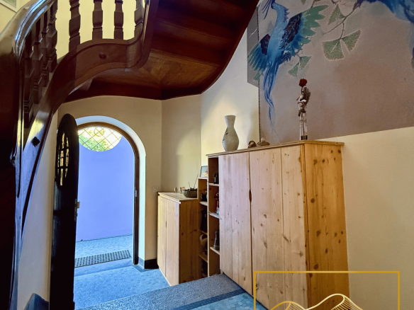 Intérieur d'un manoir avec un escalier en bois et des murs décorés.