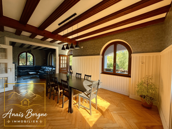 Intérieur d'un manoir avec un grand espace de vie, des poutres apparentes et une grande table à manger.