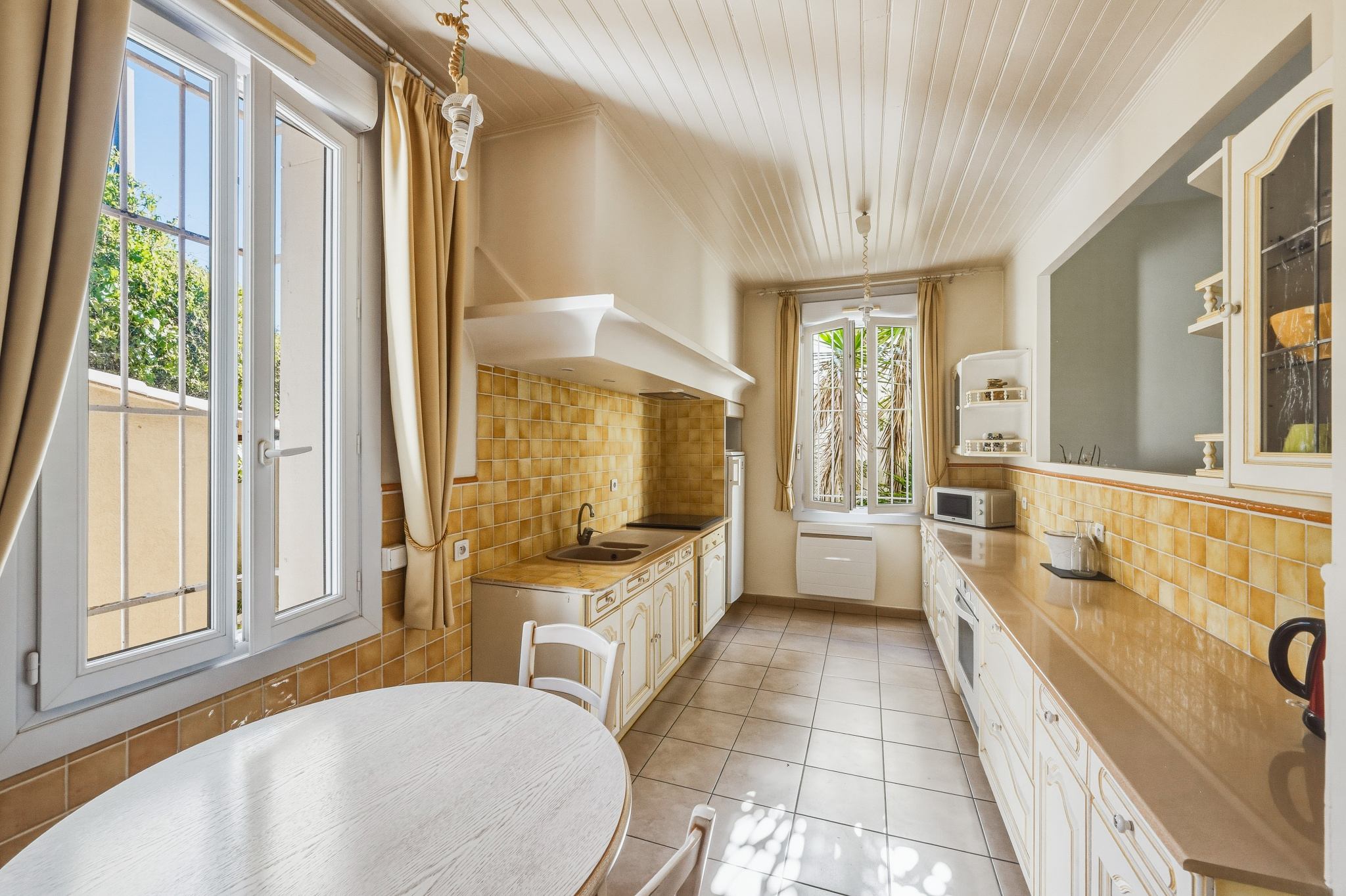 Cuisine de maison à Saint-Raphaël Cuisine lumineuse avec carrelage beige et fenêtres, dans une maison de caractère à Saint-Raphaël.