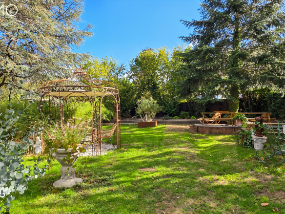Jardin paysager avec un gazebo, des arbres et des espaces de détente à Arpajon.