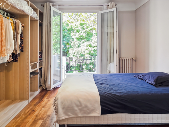 Chambre avec lit et placard intégré, fenêtre ouverte sur un jardin à Arpajon.