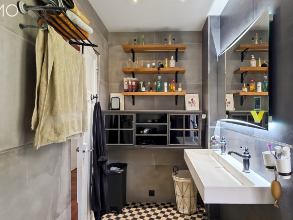 Salle de bain moderne avec murs en carrelage gris, étagères en bois et lavabo contemporain.