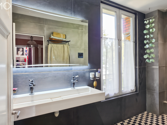 Salle de bain moderne avec lavabo double, miroir lumineux et carrelage noir et blanc.