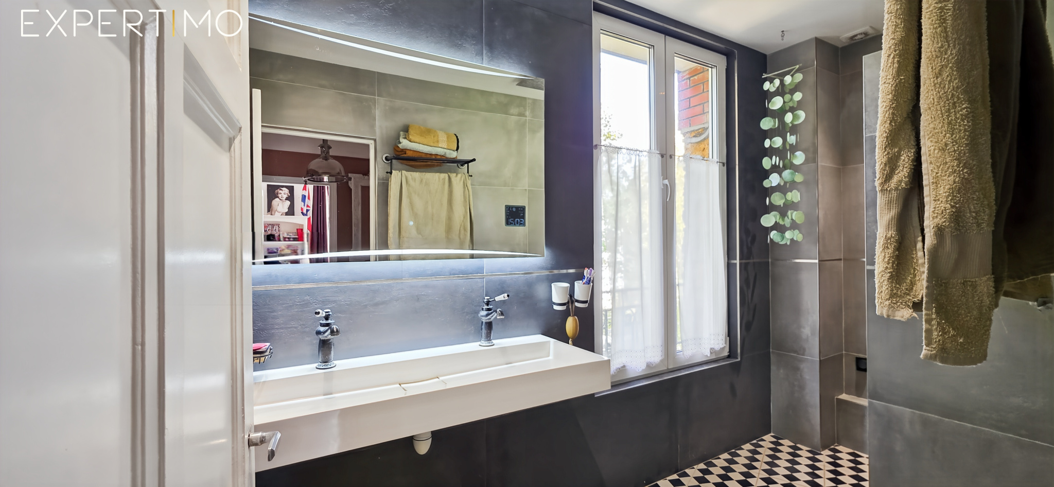 Salle de bain contemporaine Salle de bain moderne avec lavabo double, miroir lumineux et carrelage noir et blanc.