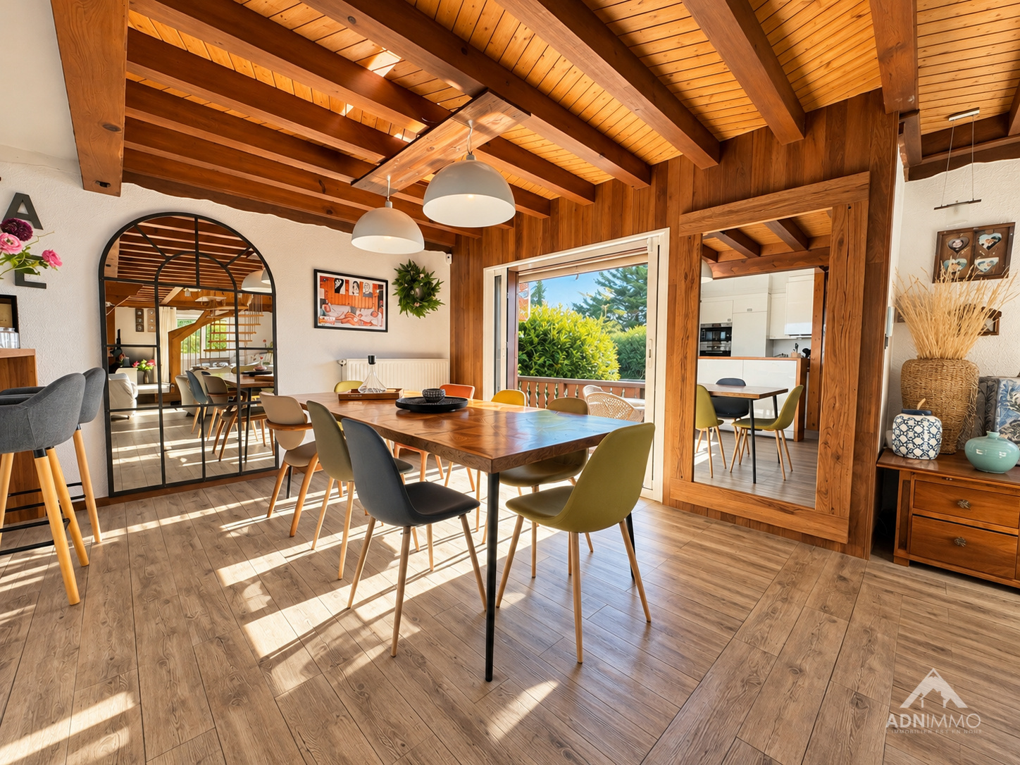 Intérieur d'un chalet rénové avec une table à manger et des chaises, lumière naturelle abondante.