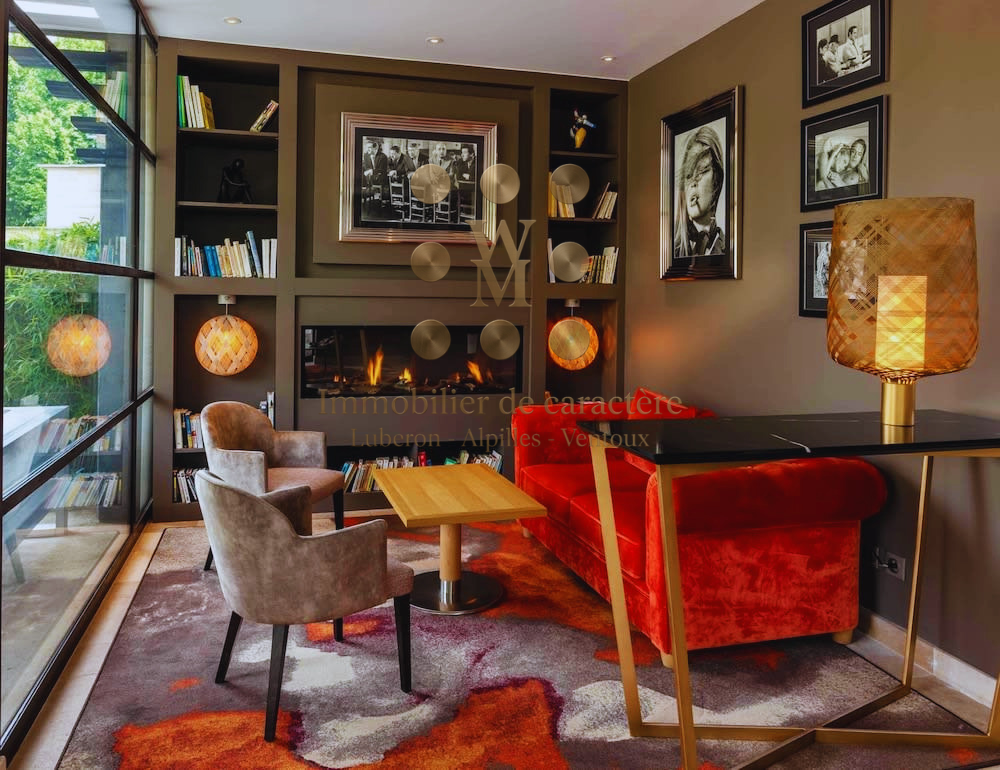 Living room of a historic property in L'Isle-sur-la-Sorgue Interior of a property with a modern living room, armchairs and a library.