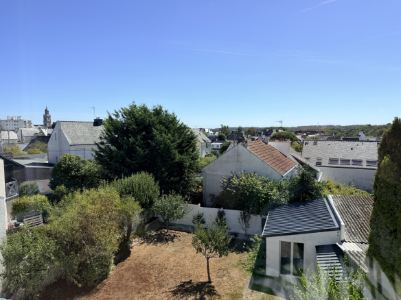 Vue sur des maisons et un jardin à Auray, ciel dégagé et ensoleillé.