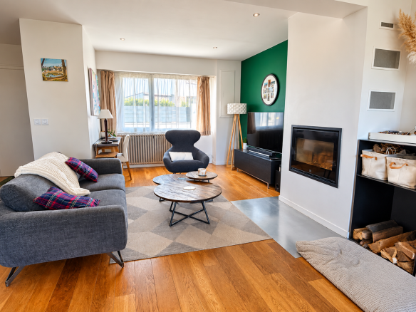 Intérieur d'une maison à Auray avec un salon moderne, cheminée et parquet en bois.