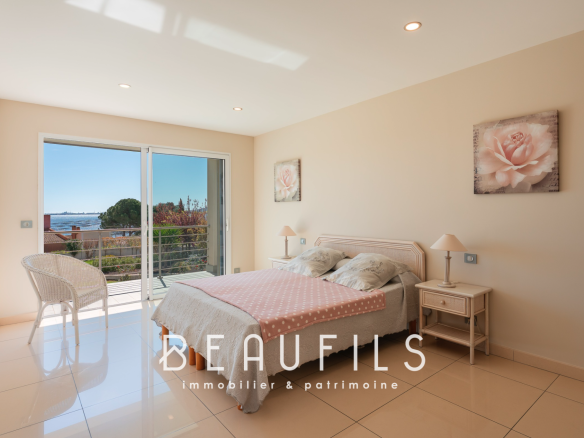 Chambre lumineuse d'une villa à Sète avec vue sur l'extérieur et accès à un balcon.