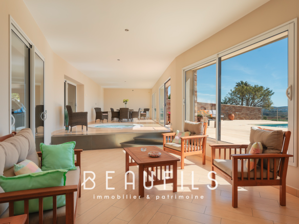 Intérieur d'une villa moderne avec salon lumineux et vue sur la piscine.