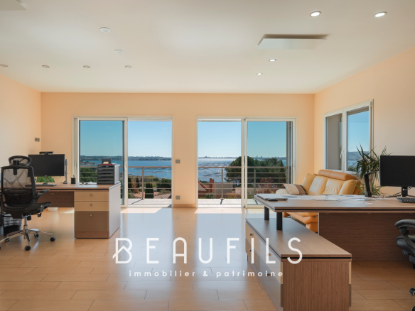 Intérieur d'une villa moderne avec vue sur l'étang de Thau, bureaux et grandes baies vitrées.