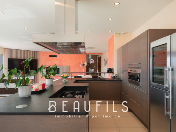 Cuisine moderne d'une villa spacieuse avec îlot central et équipements haut de gamme.