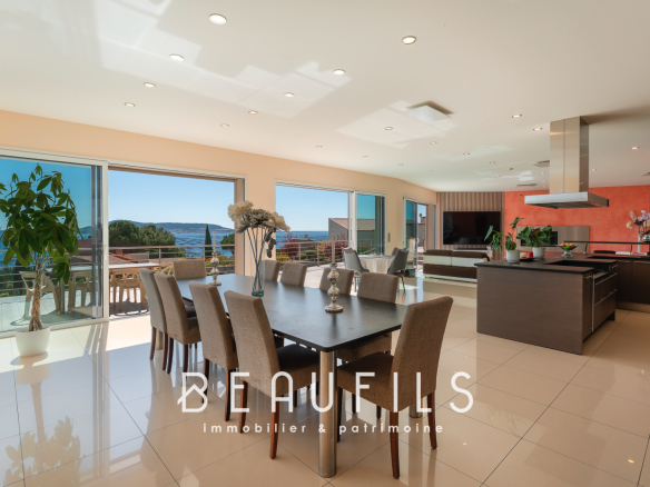 Intérieur d'une villa moderne avec vue sur la mer, salle à manger et cuisine ouverte.