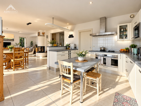 Cuisine moderne et spacieuse avec table à manger, ouverte sur un salon lumineux.