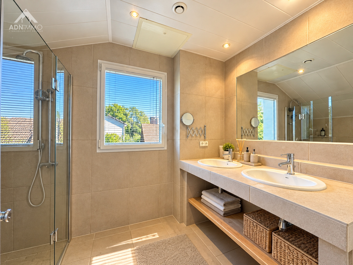 Salle de bain spacieuse Salle de bain moderne avec douche et double vasque, fenêtres offrant une vue dégagée.