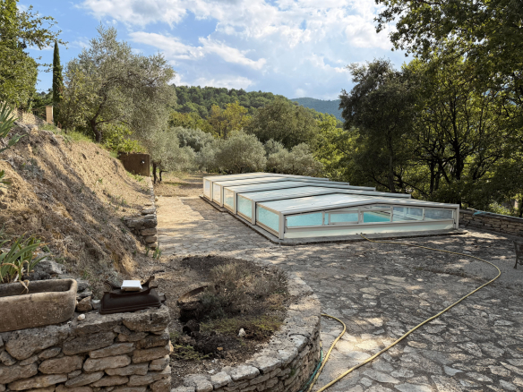 Maison de plain-pied avec piscine à Ménerbes, entourée d'arbres et de verdure.