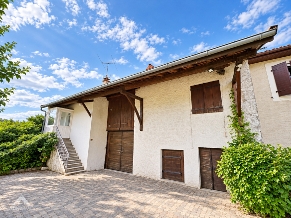 Grange gessienne rénovée du XIXe siècle avec façade blanche et volets en bois, située à Collonges.