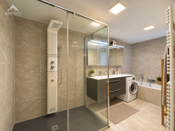 Salle de bain moderne avec douche, baignoire et espace buanderie.