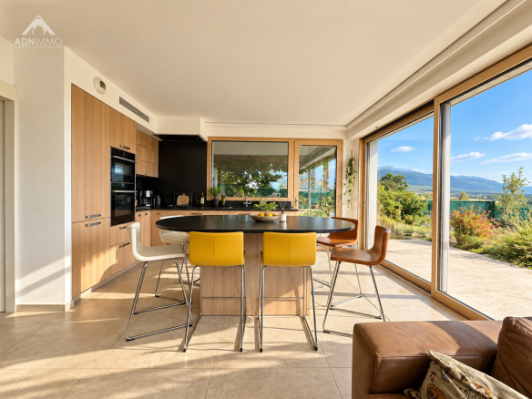 Intérieur d'une maison moderne avec cuisine ouverte et vue sur la nature.