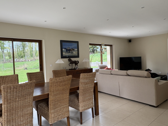 Intérieur d'une propriété avec salon et salle à manger, vue sur le jardin.