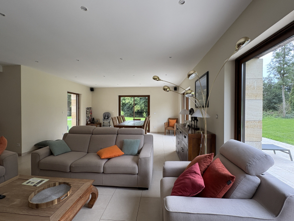 Intérieur d'une propriété moderne avec salon spacieux et fenêtres donnant sur le jardin.