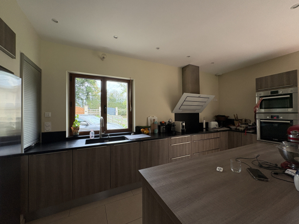 Cuisine moderne avec plans de travail en bois et fenêtre donnant sur l'extérieur.