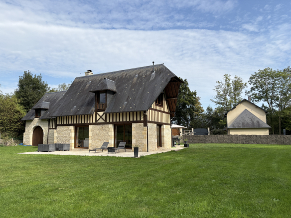 Maison de charme en pierre et bois avec jardin verdoyant en Normandie.